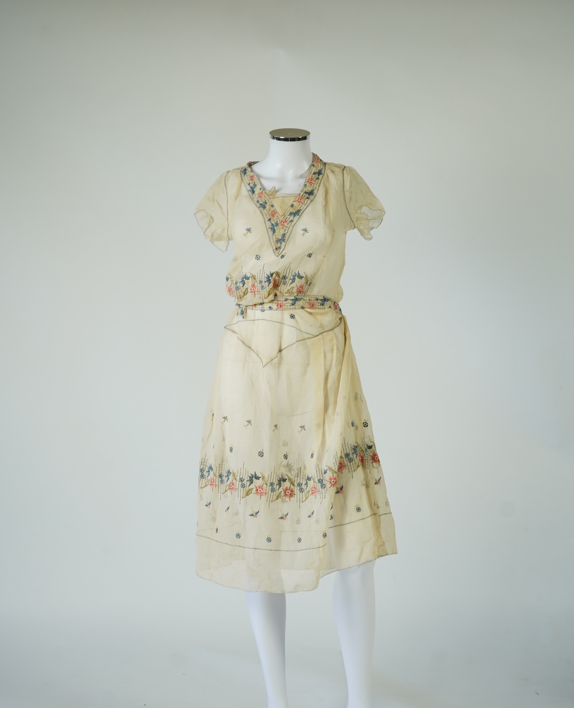 An unusual 1920's fine cream lawn summer dress with hand embroidered blue, pink, flowers, tie and picot edging., 116cm long. Condition - some small rust stains and one small tear at the back right shoulder.